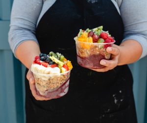chef at portside holding two acai bowls topped with fruit